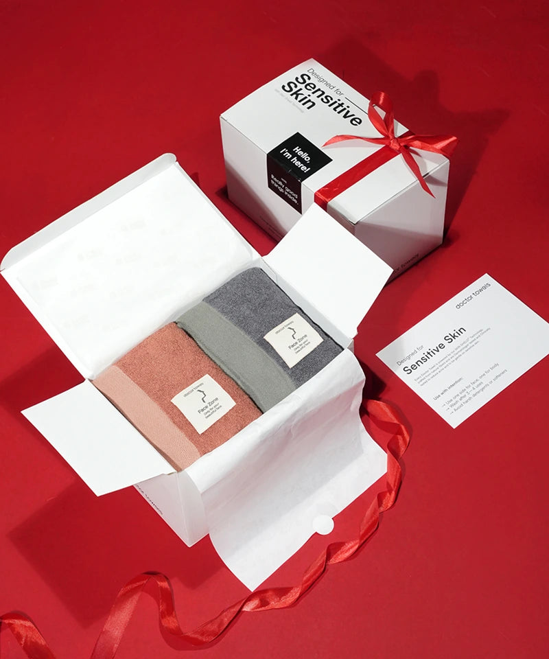 Two towels in a white box , Product packaging with a red ribbon on a red background
